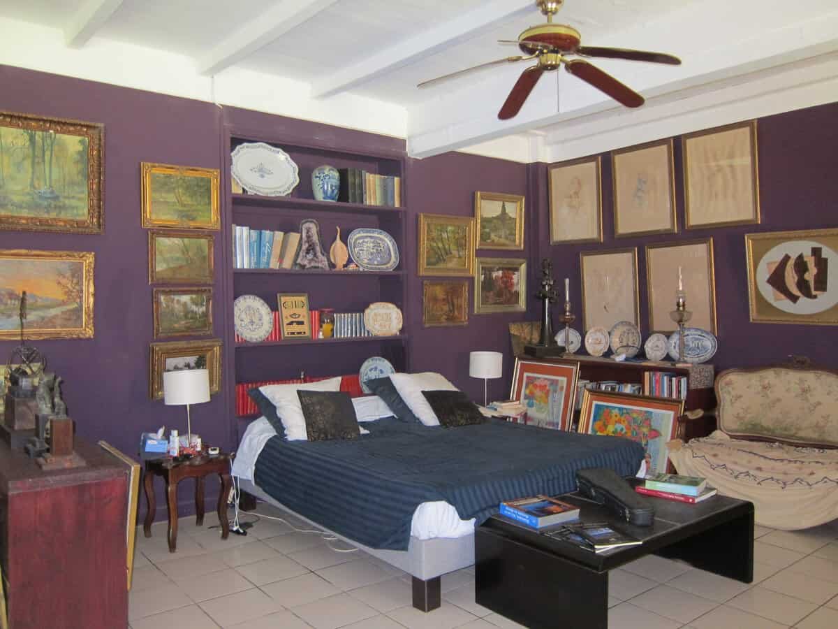 Chambre aux murs aubergine, tableaux anciens et bibliothèque maçonnée à l’Habitation de l’Enclos